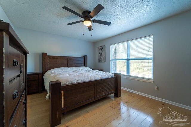 bedroom featuring ceiling fan, a textured ceiling, and light hardwood / wood-style flooring