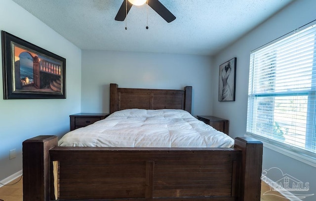 bedroom featuring multiple windows, ceiling fan, and a textured ceiling