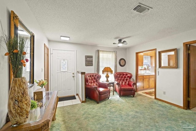 sitting room with carpet, ceiling fan, sink, and a textured ceiling