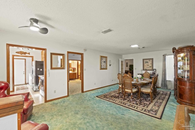 carpeted dining space with ceiling fan and a textured ceiling