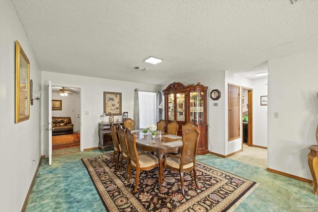 carpeted dining room with a textured ceiling and ceiling fan