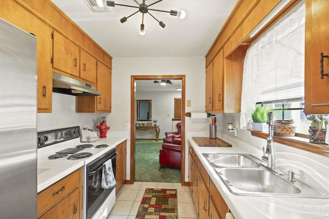 kitchen featuring a textured ceiling, sink, white electric range, stainless steel refrigerator, and light tile patterned flooring