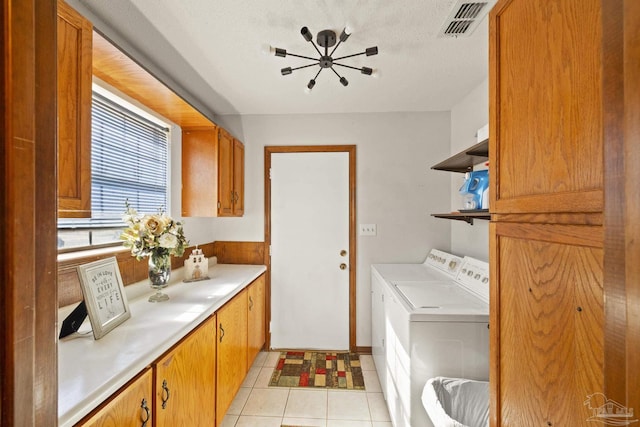 laundry area with washer and dryer, light tile patterned flooring, cabinets, and a textured ceiling