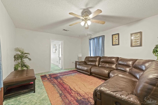 carpeted living room featuring a textured ceiling and ceiling fan