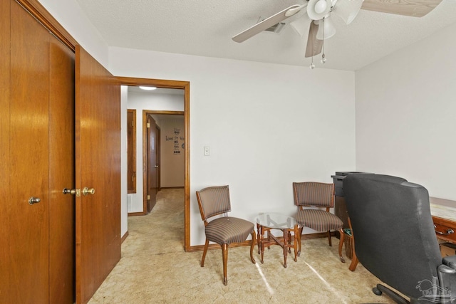 office space featuring ceiling fan, light colored carpet, and a textured ceiling