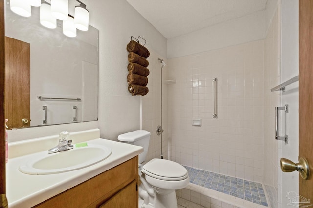 bathroom featuring a tile shower, vanity, and toilet