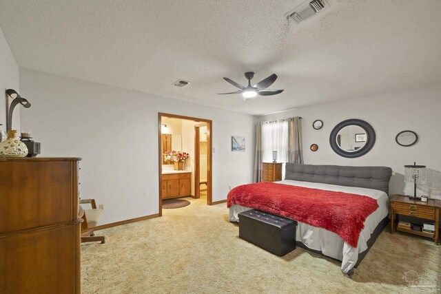 carpeted bedroom with ceiling fan, ensuite bathroom, and a textured ceiling