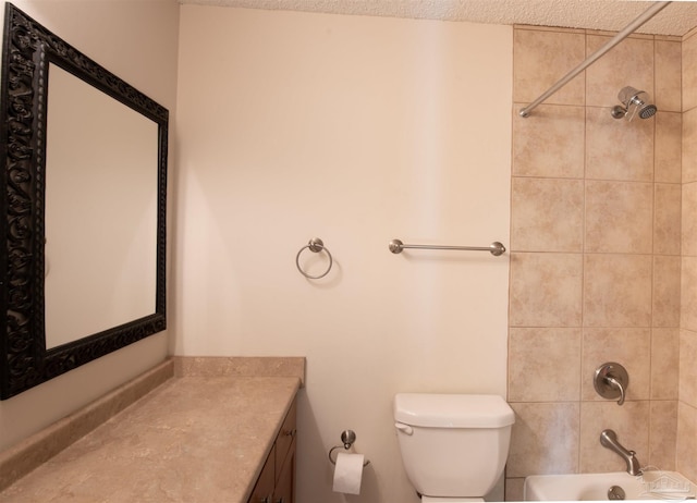 full bathroom featuring vanity, a textured ceiling, tiled shower / bath combo, and toilet