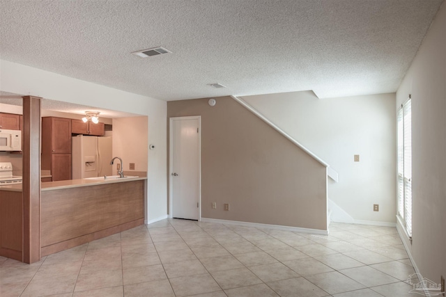 interior space with light tile patterned flooring, sink, and a textured ceiling