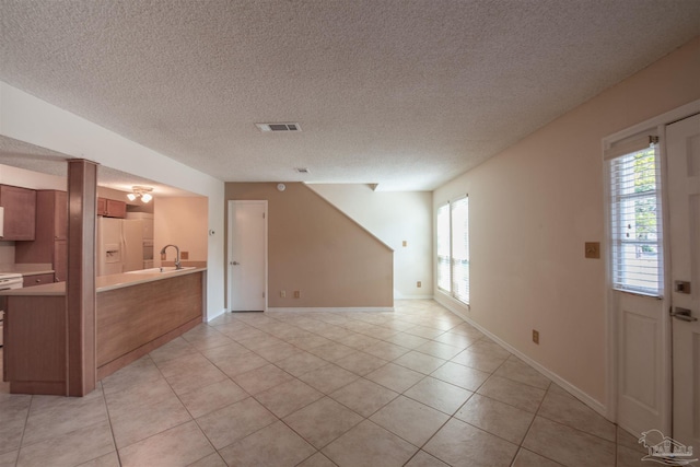 unfurnished room featuring a textured ceiling and light tile patterned flooring