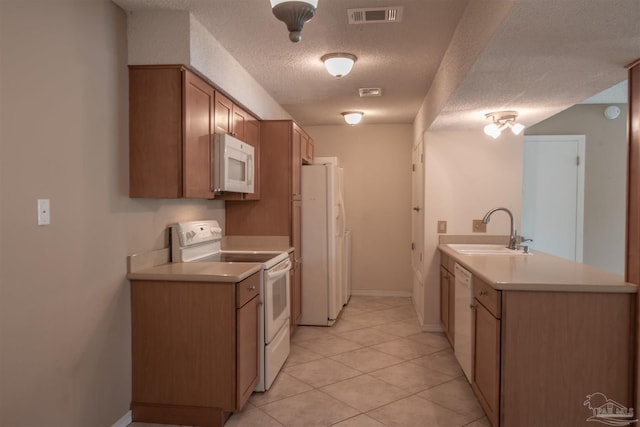 kitchen featuring sink, light tile patterned floors, white appliances, kitchen peninsula, and a textured ceiling