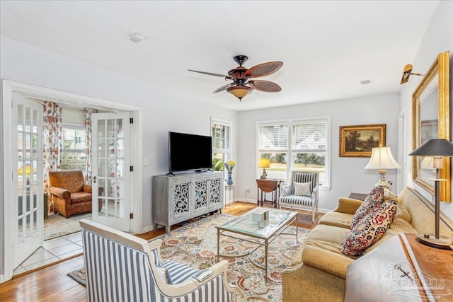 living area featuring a healthy amount of sunlight, ceiling fan, wood finished floors, and french doors