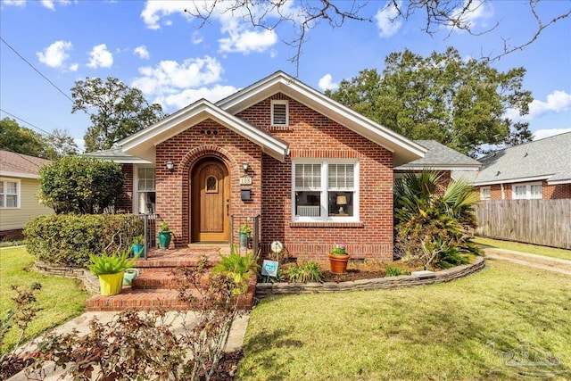 view of front facade featuring brick siding, a front lawn, and fence