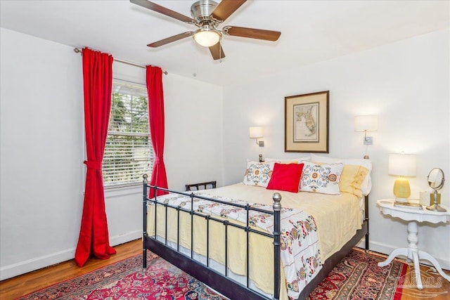 bedroom with a ceiling fan, baseboards, and wood finished floors