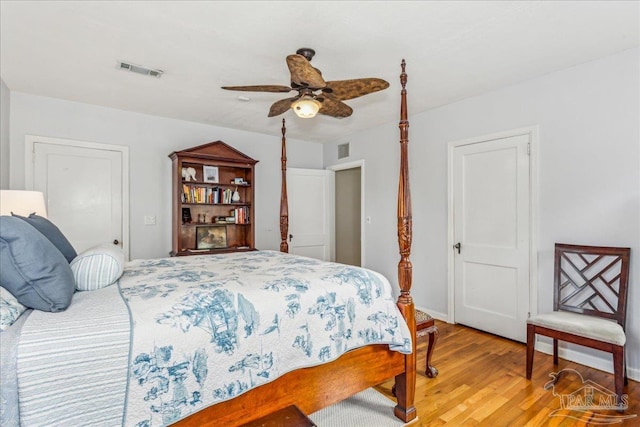 bedroom featuring baseboards, wood finished floors, visible vents, and a ceiling fan