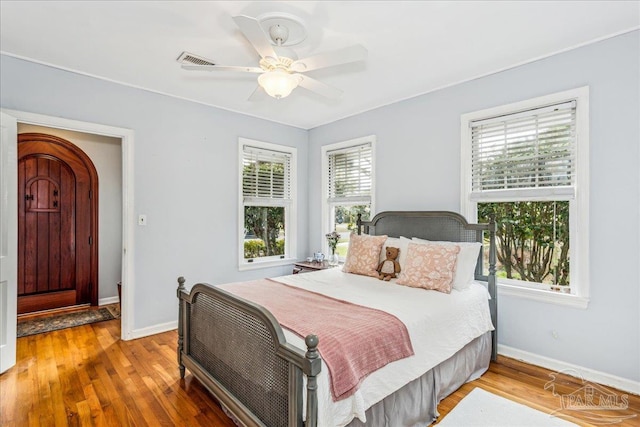 bedroom with baseboards, visible vents, ceiling fan, and wood finished floors