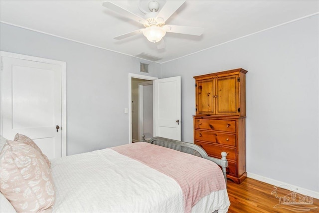 bedroom featuring baseboards, visible vents, a ceiling fan, and wood finished floors