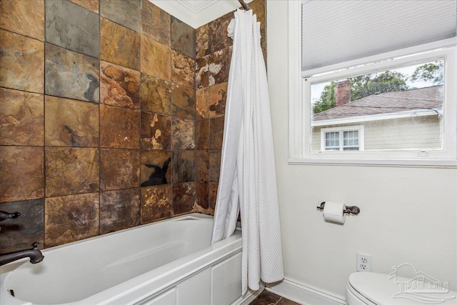 bathroom featuring baseboards, toilet, and shower / bathtub combination with curtain