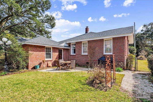 back of property featuring brick siding, a yard, a gate, a chimney, and a patio area