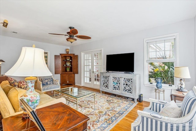 living room featuring a ceiling fan, plenty of natural light, visible vents, and wood finished floors