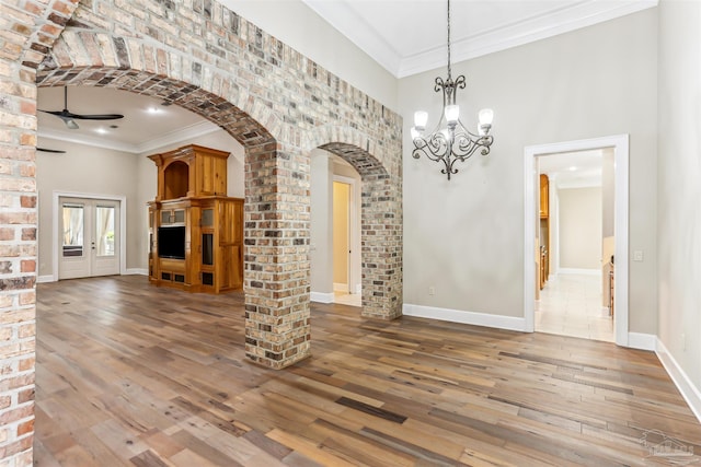 unfurnished dining area with hardwood / wood-style flooring, arched walkways, and crown molding