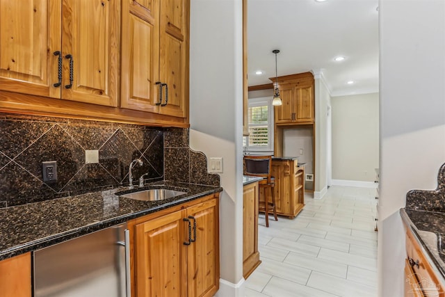 kitchen featuring recessed lighting, a sink, dark stone counters, decorative backsplash, and brown cabinetry