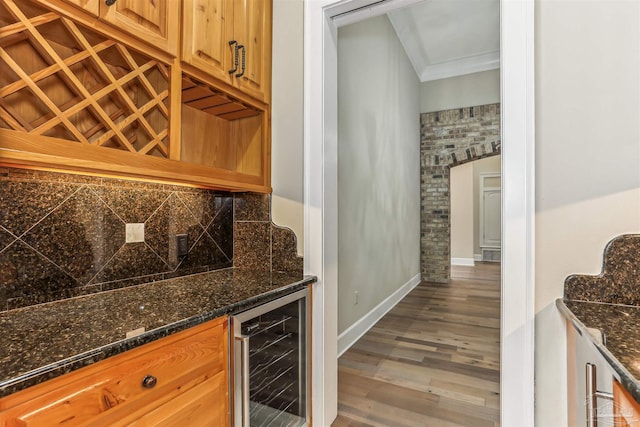 bar with wood finished floors, wine cooler, baseboards, and ornamental molding