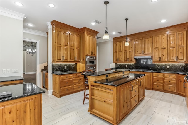 kitchen featuring under cabinet range hood, visible vents, crown molding, a center island, and decorative backsplash