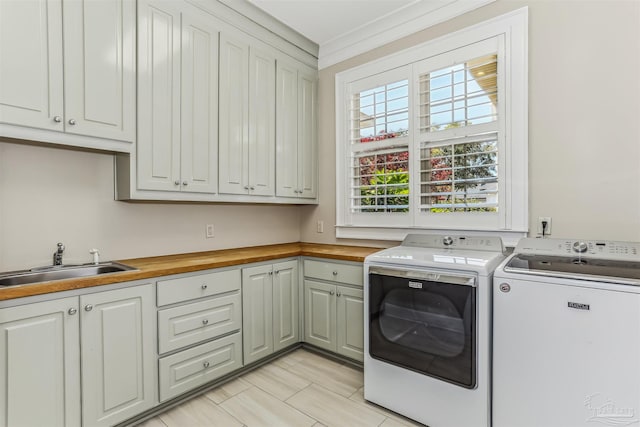 clothes washing area with washer and dryer, cabinet space, and a sink