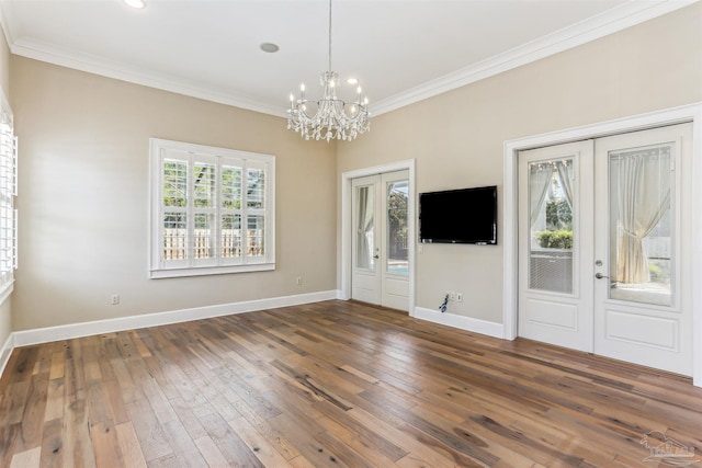 unfurnished living room with french doors, an inviting chandelier, hardwood / wood-style flooring, and crown molding