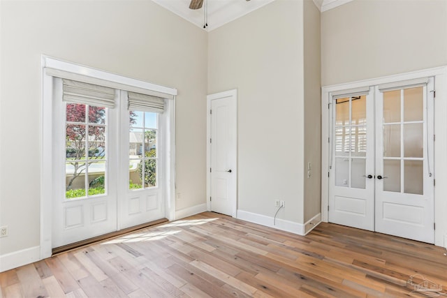 foyer entrance with high vaulted ceiling, baseboards, french doors, and light wood-type flooring