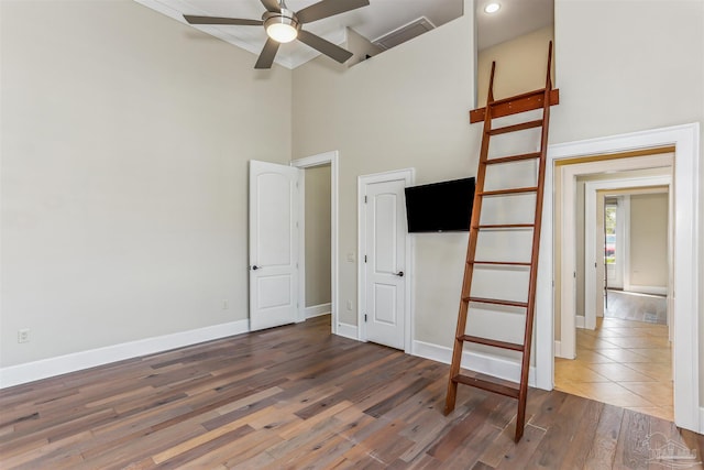 unfurnished bedroom featuring a high ceiling, wood finished floors, and baseboards