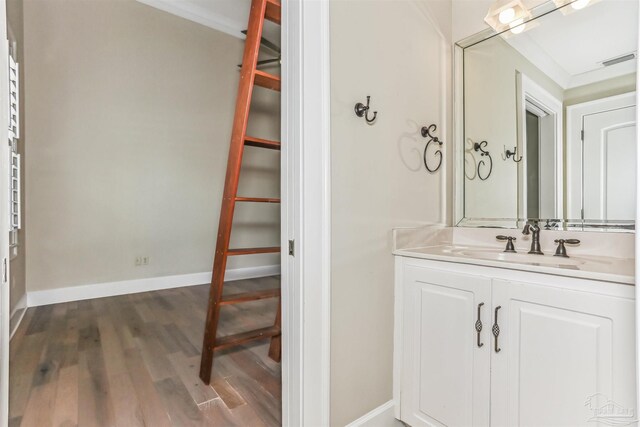 bathroom featuring baseboards, vanity, wood finished floors, and visible vents