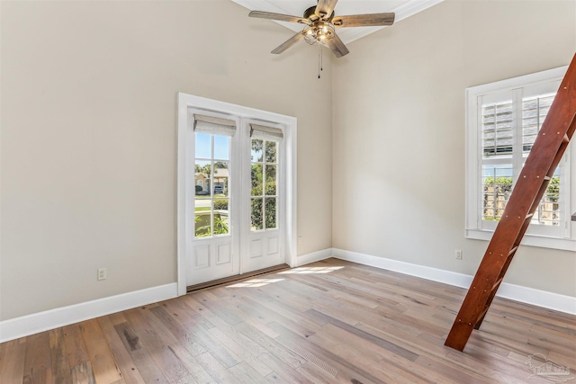 empty room with light wood-type flooring, a ceiling fan, and baseboards