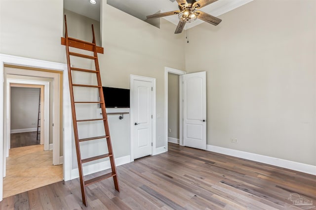 unfurnished bedroom featuring baseboards, wood finished floors, and a towering ceiling