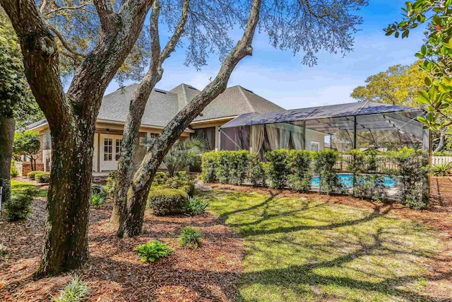 rear view of property with a lawn, an outdoor pool, glass enclosure, and stucco siding