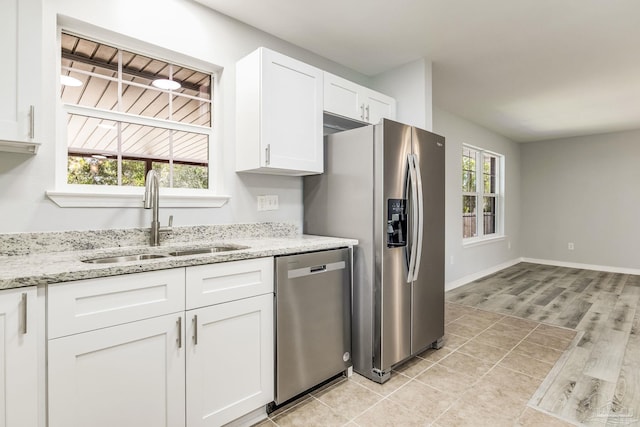 kitchen featuring sink, stainless steel appliances, light stone countertops, white cabinets, and light wood-type flooring