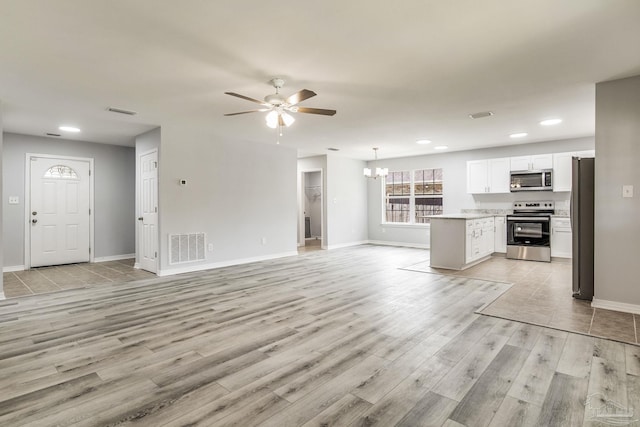 unfurnished living room with ceiling fan with notable chandelier and light hardwood / wood-style flooring