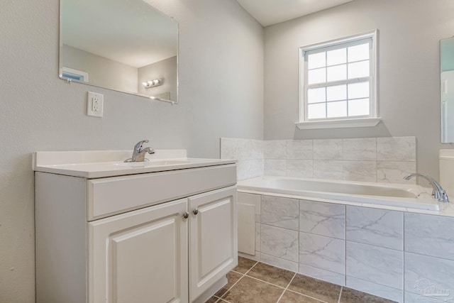 bathroom with tile patterned floors, vanity, and tiled tub