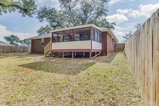 rear view of house featuring a sunroom and a lawn