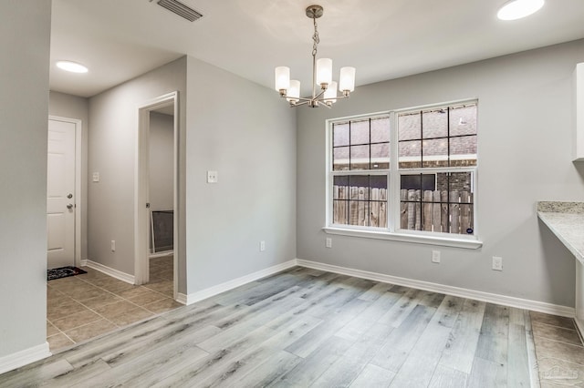 unfurnished dining area featuring an inviting chandelier and light hardwood / wood-style floors