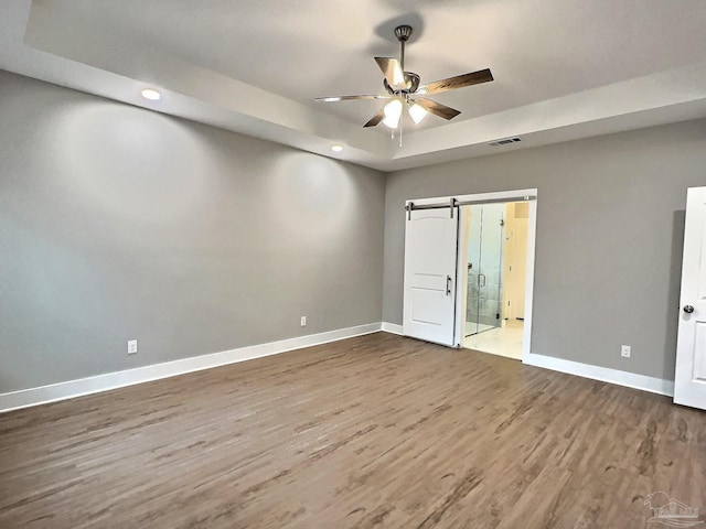 unfurnished room with ceiling fan, a tray ceiling, and hardwood / wood-style floors