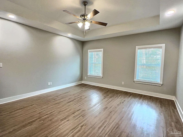 spare room featuring dark hardwood / wood-style floors, ceiling fan, and a tray ceiling