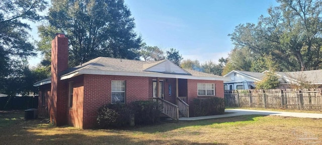 exterior space featuring central AC unit, fence, a front lawn, and brick siding