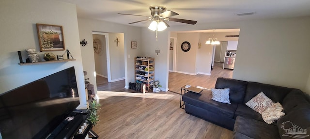 living area featuring a fireplace, wood finished floors, visible vents, and baseboards