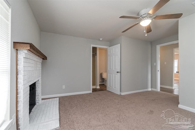 unfurnished living room with ceiling fan, light colored carpet, baseboards, a brick fireplace, and a wealth of natural light