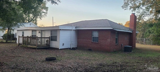 rear view of property featuring brick siding, a chimney, crawl space, central AC, and a deck