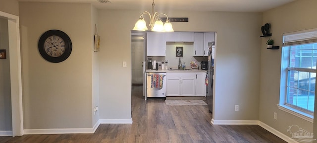 kitchen featuring white cabinets, hanging light fixtures, stainless steel appliances, light countertops, and a chandelier