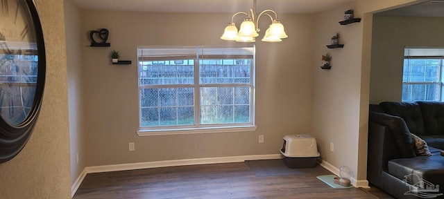 dining room featuring a notable chandelier, baseboards, dark wood-style flooring, and a wealth of natural light