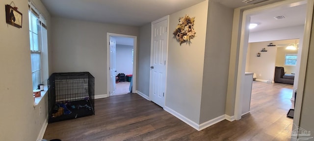 hallway featuring dark wood-type flooring, visible vents, and baseboards